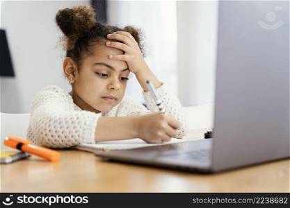 side view worried little girl home during online school with laptop