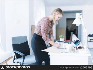 side view young businesswoman standing near desk writing office