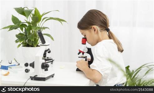 side view young girl looking into microscope