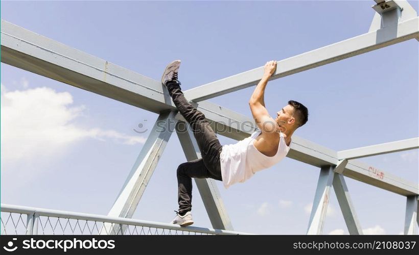side view young man climbing ceiling bridge