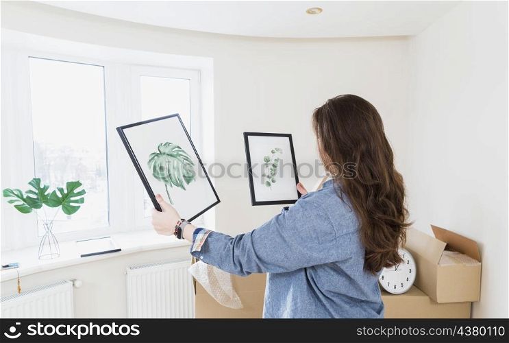 side view young woman choosing picture frame her new home