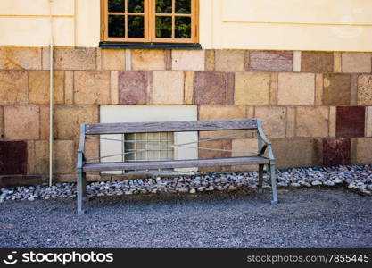 sidewalk scene with wooden bench and brick wall