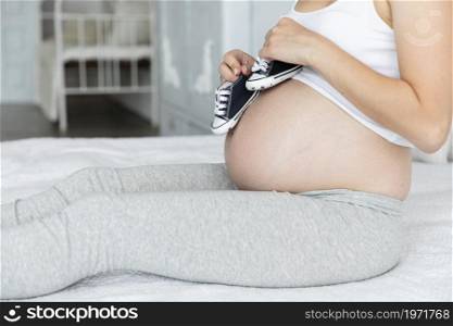 sideways pregnant woman playing little shoes. High resolution photo. sideways pregnant woman playing little shoes. High quality photo