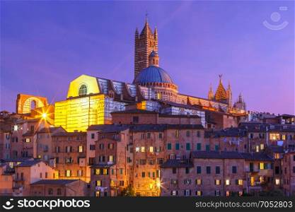 Siena Cathedral at night, Tuscany, Italy. Beautiful view of Dome and campanile of Siena Cathedral, Duomo di Siena, and Old Town of medieval city of Siena during evening blue hour, Tuscany, Italy