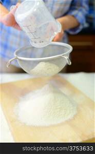 Sifting the flour. Cooking: woman sifting the flour with sieve