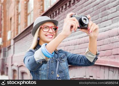 Sightseeing in new city. Female young traveler walking on street and taking photo on old camera
