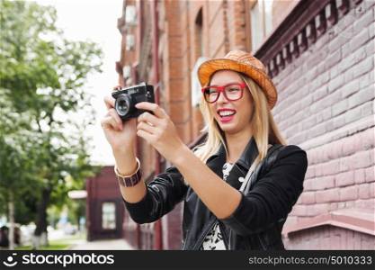 Sightseeing in new city. Female young traveler walking on street and taking photo on old camera