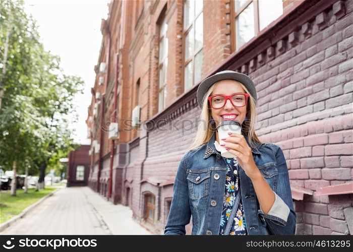 Sightseeing in touristic city. Happy tourist girl with coffee cup walking on city street
