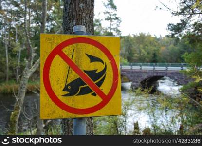 Sign No fishing at a river with an old bridge in background