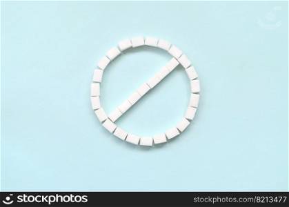 Sign of the ban of sugar cubes on a pastel blue background. Diabetic concept. Refusing sugar. Flat lay minimal top view. Sign of the ban of sugar cubes on a pastel blue background