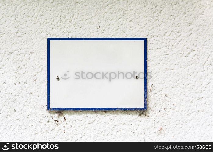 Sign or panel mounted with blue border without inscription on a wall.