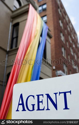 Signboard in front of a rainbow flag hanging from a building