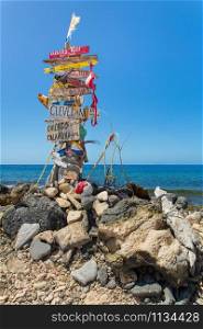 Signpost with stones at beach with blue ocean on island Bonaire