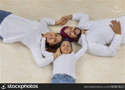 SIKH BOY HAPPILY HUGGING MOTHER AND FATHER WHILE LYING ON FLOOR AND POSING