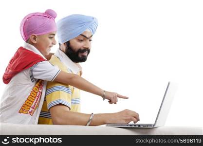 Sikh boy pointing at his fathers laptop