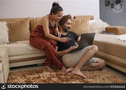 Sikh Couple shopping online together through laptop by using credit card