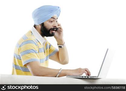 Sikh man talking on the phone while working on a laptop