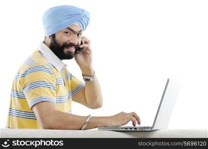 Sikh man talking on the phone while working on a laptop