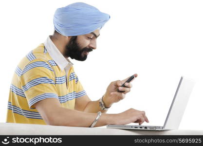 Sikh man with a mobile phone and a laptop