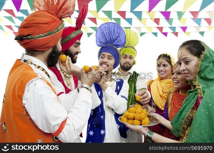 Sikh people eating laddoos