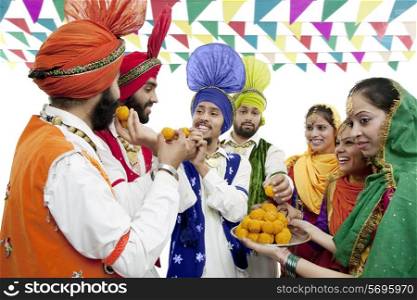 Sikh people eating laddoos
