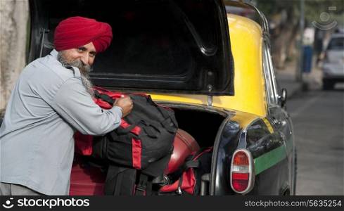 Sikh taxi driver loading luggage into the dickie