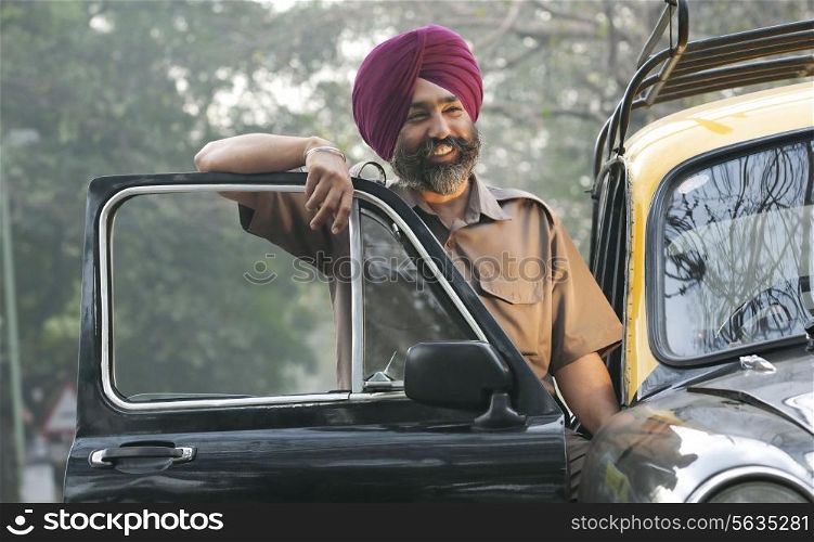 Sikh taxi driver standing next to his vehicle