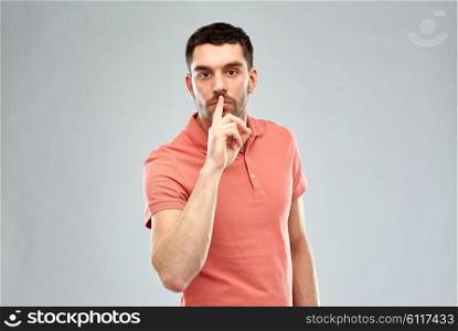 silence, gesture and people concept - serious young man making hush sign over gray background