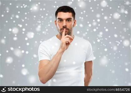 silence, gesture, winter, christmas and people concept - young man making hush sign over gray background
