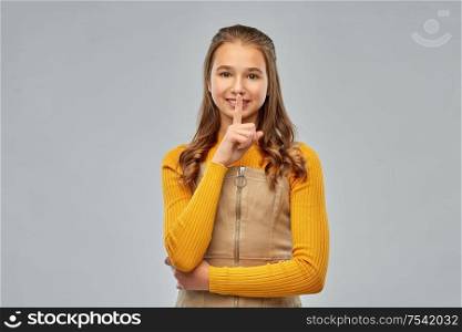 silence, secret and confidentiality concept - young teenage girl making hush gesture over grey background. young teenage girl making hush gesture
