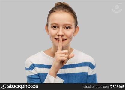 silence, secret and people concept - smiling teenage girl making hush gesture with finger on lips over grey background. smiling teenage girl with finger on lips