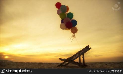 Silhouette balloon on the beach during the sunset in summer time. multicolored of balloon holding on seat.