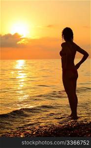 Silhouette beautiful woman standing on beach on sunset