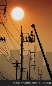 Silhouette electricians on crane truck are working to maintenance electrical system on power pole with blurred building shadow in sunrise sky background, illustration mode