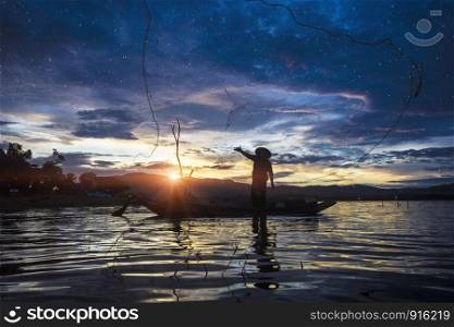 Silhouette Fisherman Fishing by using Net on the boat with sunlight in Thailand , Nature and Culture concept