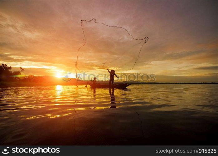 Silhouette Fisherman Fishing by using Net on the boat with sunshine in Thailand in the morning ,Nature and Culture concept