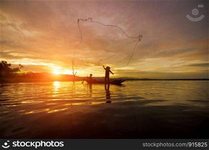 Silhouette Fisherman Fishing by using Net on the boat with sunshine in Thailand in the morning ,Nature and Culture concept