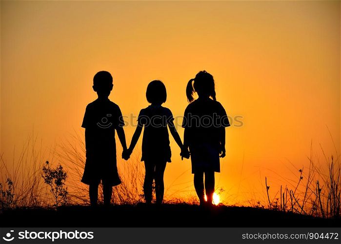 Silhouette friendship of three on mountain with sunset background