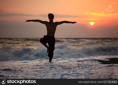 Silhouette guy yoga on sunset wavy beach