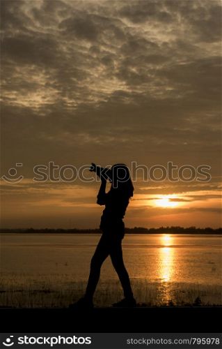 Silhouette Handsome Photographer take a photo with professional camera on the sunset.
