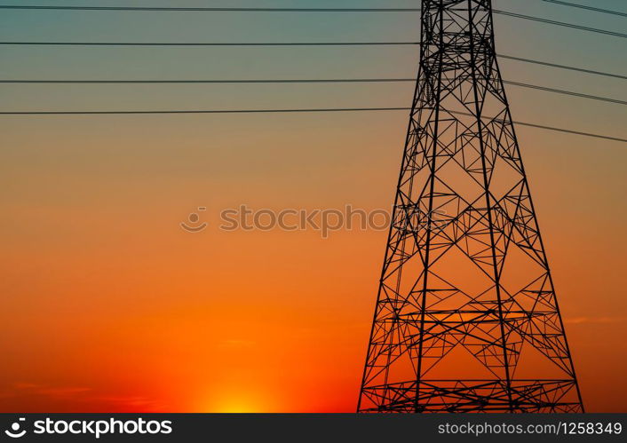 Silhouette high voltage electric pylon and electrical wire with an orange sky. Electricity poles at sunset. Power and energy concept. High voltage grid tower with wire cable at distribution station.