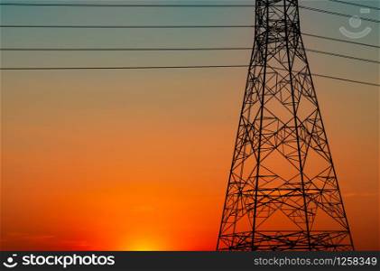 Silhouette high voltage electric pylon and electrical wire with an orange sky. Electricity poles at sunset. Power and energy concept. High voltage grid tower with wire cable at distribution station.