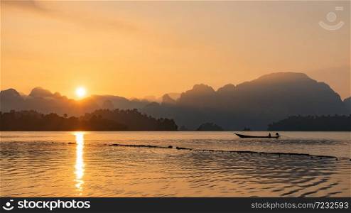 silhouette image of a boat sailing in a dam in southern of Thailand in the morning.