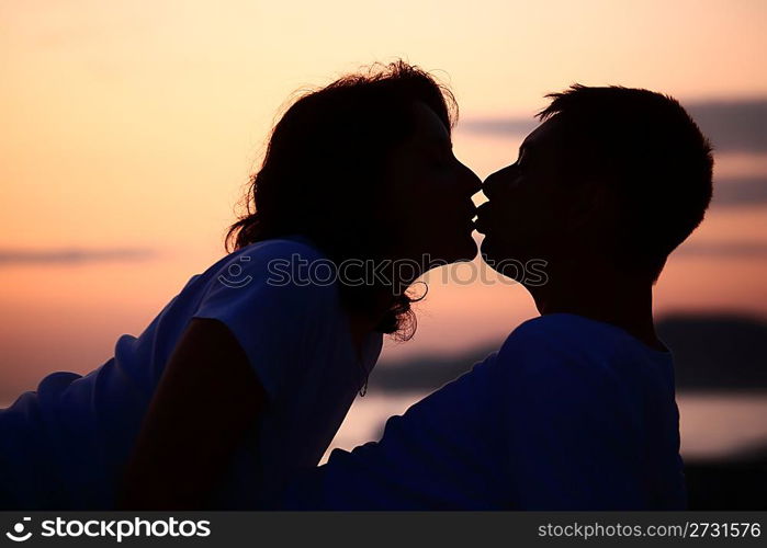 silhouette kissing man and woman on beach