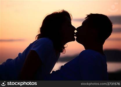 silhouette kissing man and woman on beach