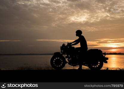 Silhouette man riding motor bike with sunset. Travel Concept