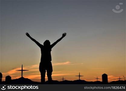 Silhouette man with hands raise up at the Cross of Jesus