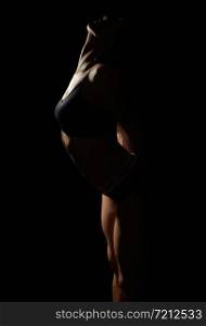 silhouette of a beautiful young girl of athletic appearance, body curved back, arms laid back, low key