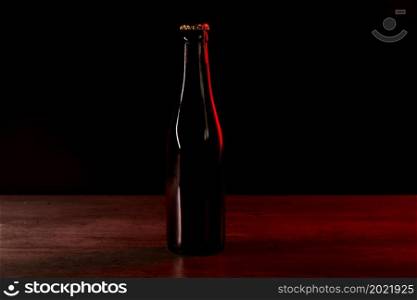 silhouette of a beer bottle on a black background with red and orange lights