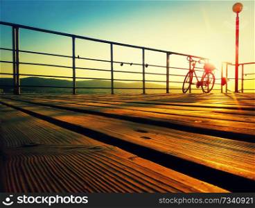 Silhouette of a bicycle on a seaside deck in the morning. Golden sunrise over the sea coast. Lifestyle background on the Sunny Beach, Nessebar, Bulgaria.